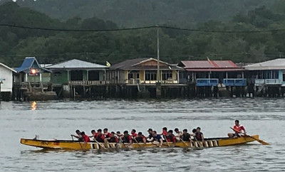 Dragon boat training with students and staff in front of the water village